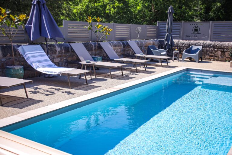 Le solarium et ses transats le long du bassin — Hôtel La Garenne, Labeaume (Ardèche)