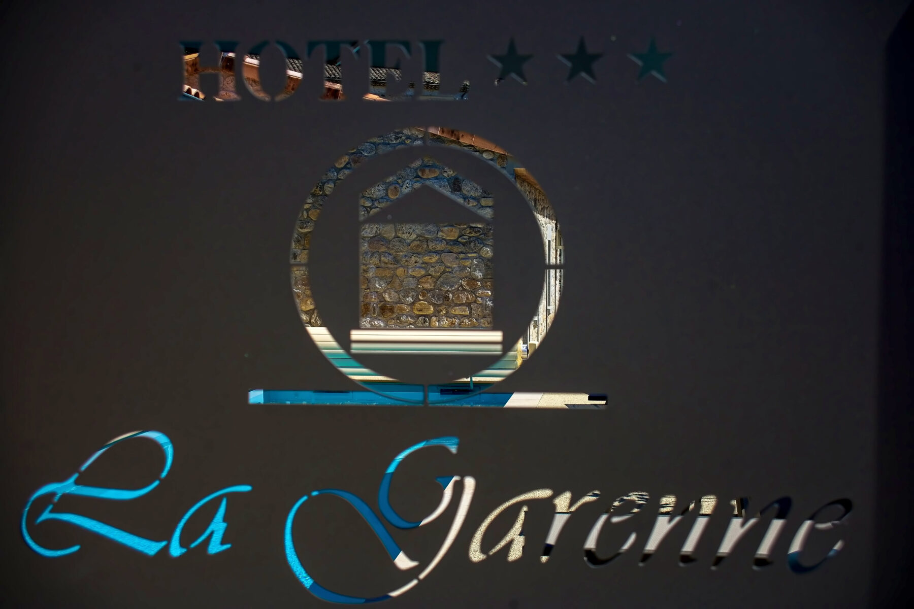 L'enseigne de l'hôtel éclairée à la tombée de la nuit — Hôtel La Garenne, Labeaume (Ardèche)