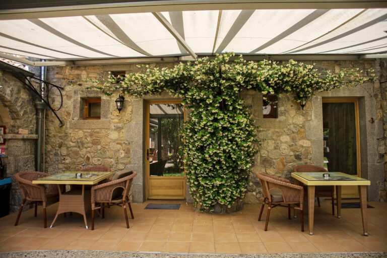 Le patio ombragé et ses tables, devant les chambres — Hôtel La Garenne, Labeaume (Ardèche)